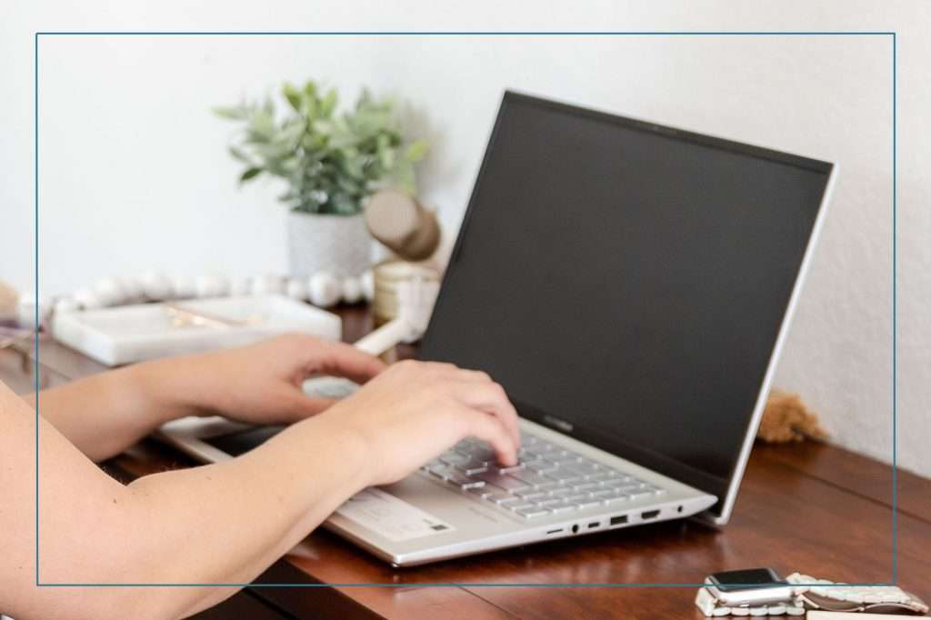 woman with her hands on the keyword of a laptop