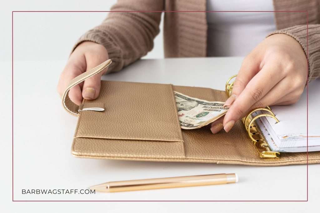 woman in brown sweater putting money in pocket of a brown three-ringed binder