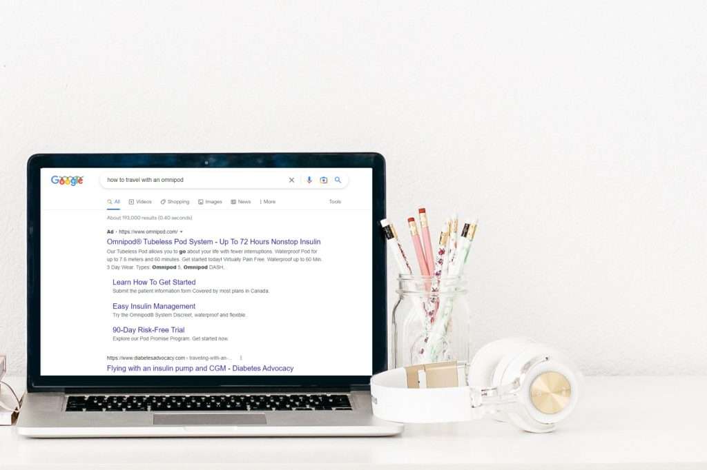 laptop showing how keyword intent can get you to the top of a search engine results page. Jar of pencils to the right and white headphones wrapped around the jar.
