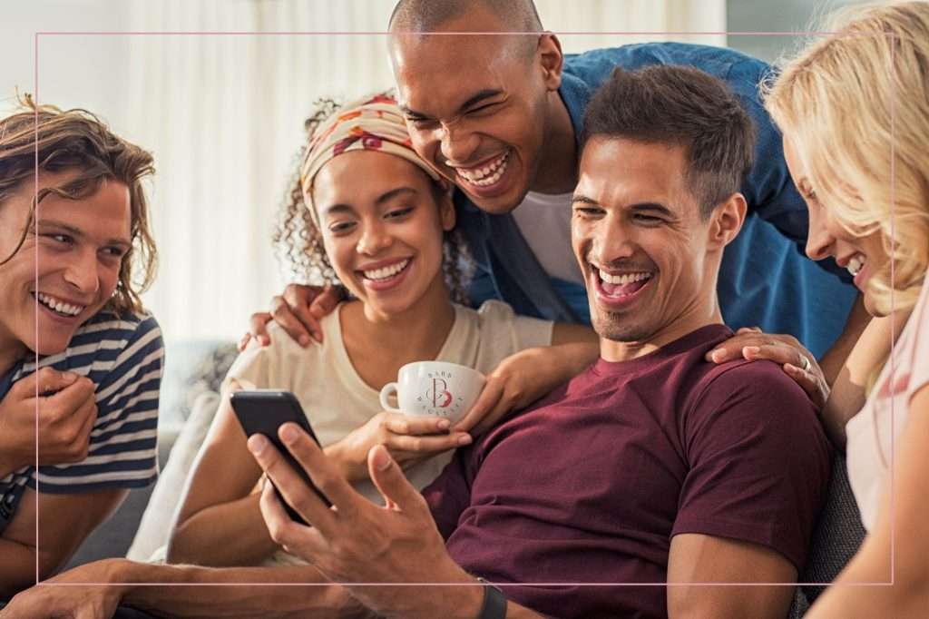 a group of people looking at a phone happy with the results.